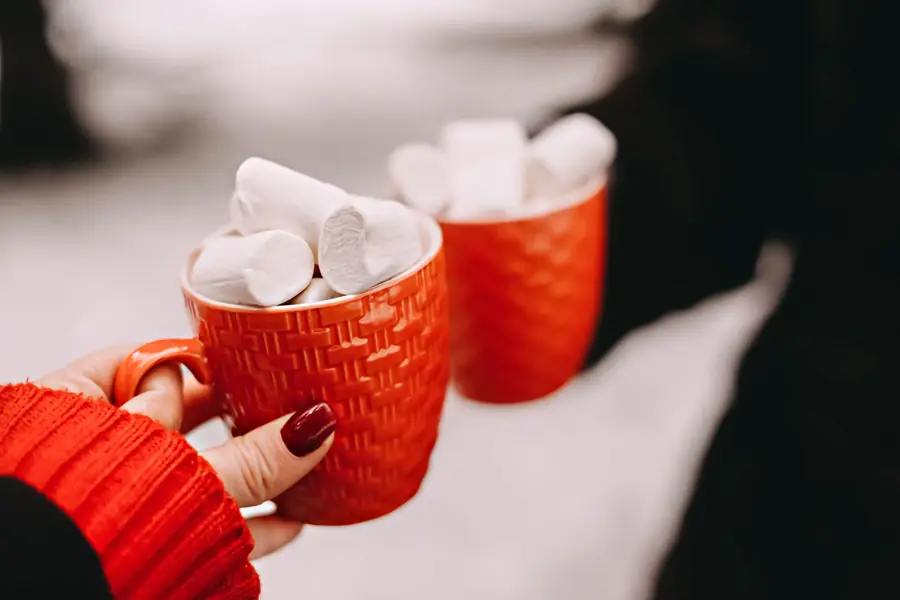 Two red mugs of hot chocolate piled with marshmallows